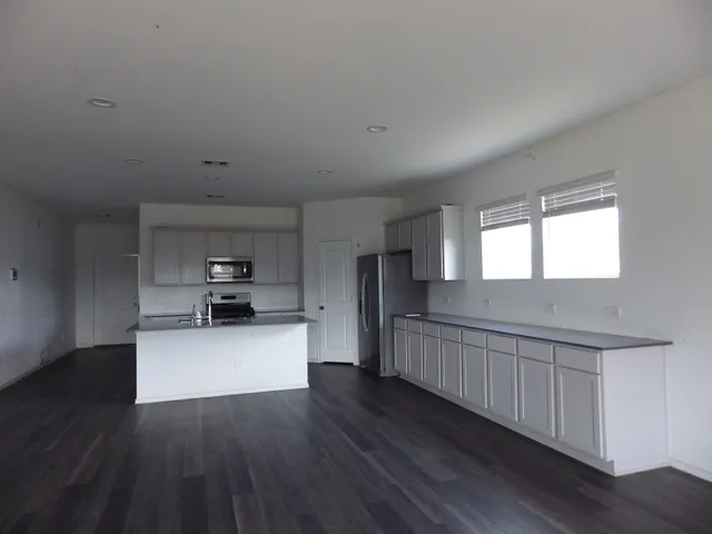a kitchen with stainless steel appliances wooden floors and white walls