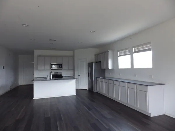 a kitchen with stainless steel appliances wooden floors and white walls