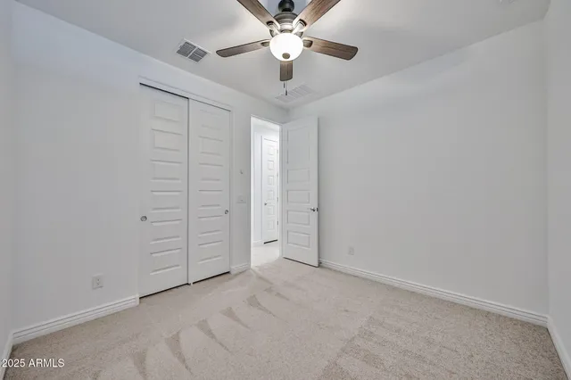 an empty room with closet and a chandelier fan