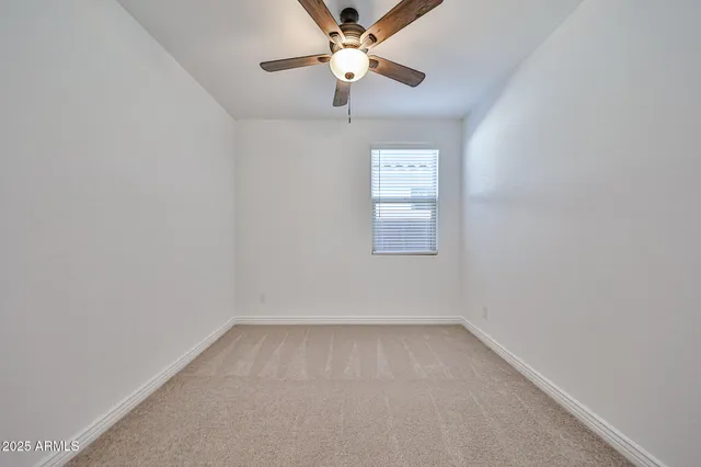 an empty room with a window and a fan
