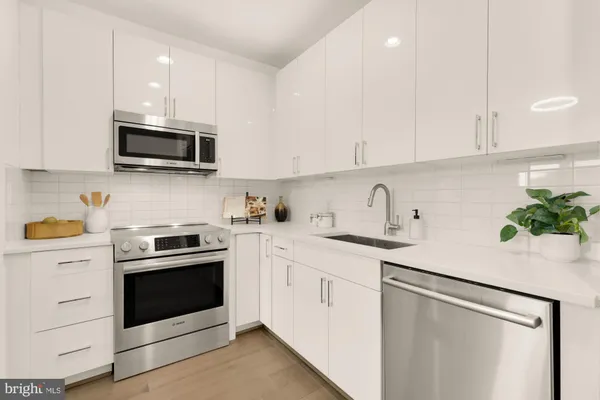 a kitchen with white cabinets stainless steel appliances and sink