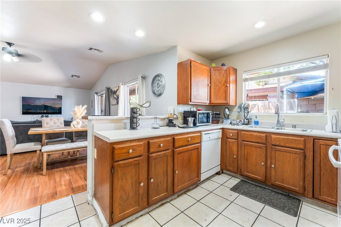 4656 East Desert Inn Road Las Vegas, NV 89121 - Photo 68 of 98 4652 E DI Kitchen featuring white dishwasher, light tile patterned floors, light countertops, a peninsula, and brown cabinetry