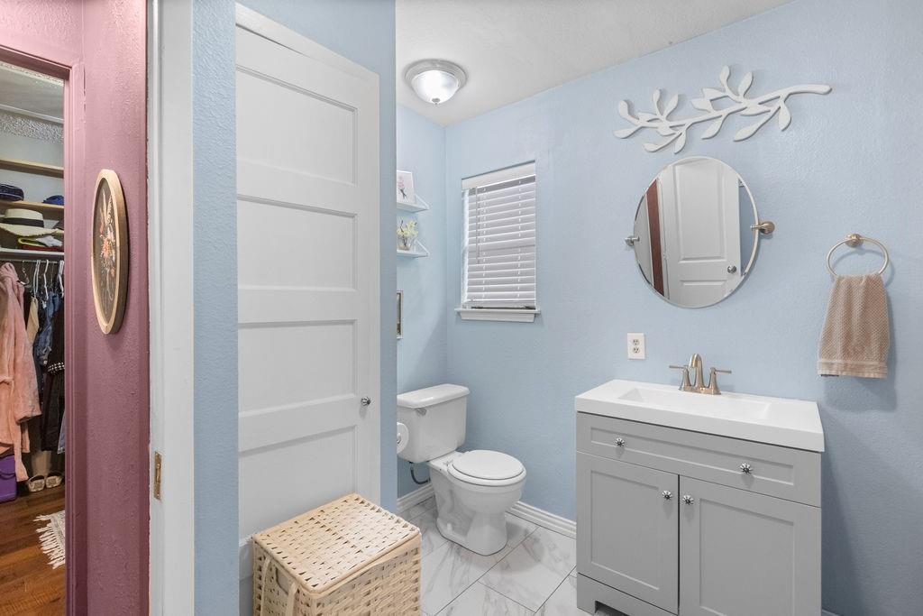 1320 Elm Street Bonham, TX 75418 - Photo 21 of 40 a bathroom with a toilet a sink and mirror