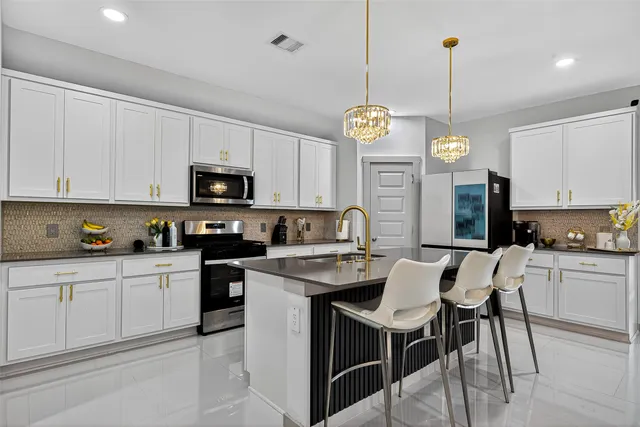 a kitchen with stainless steel appliances kitchen island granite countertop a refrigerator a stove a microwave oven a sink with a dining table and chairs