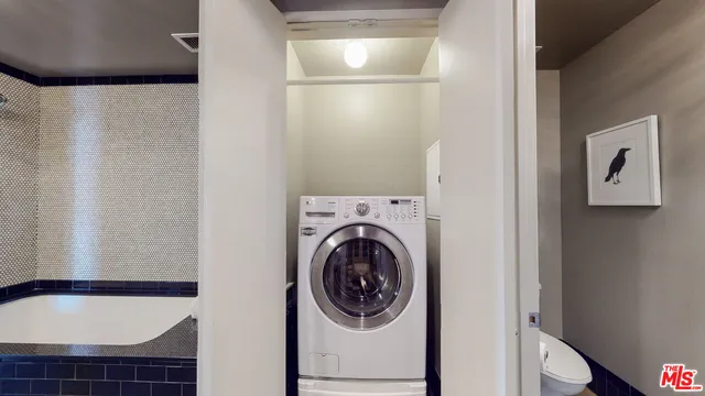 a living room with stainless steel appliances furniture a flat screen tv and kitchen view