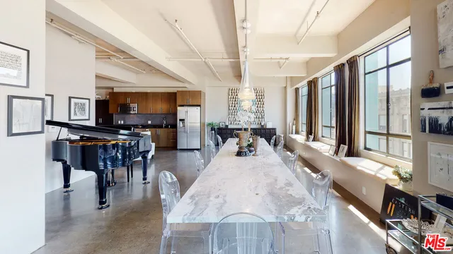 a living room with stainless steel appliances furniture a rug kitchen view and a large window