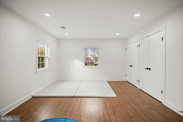 an empty room with wooden floor and windows