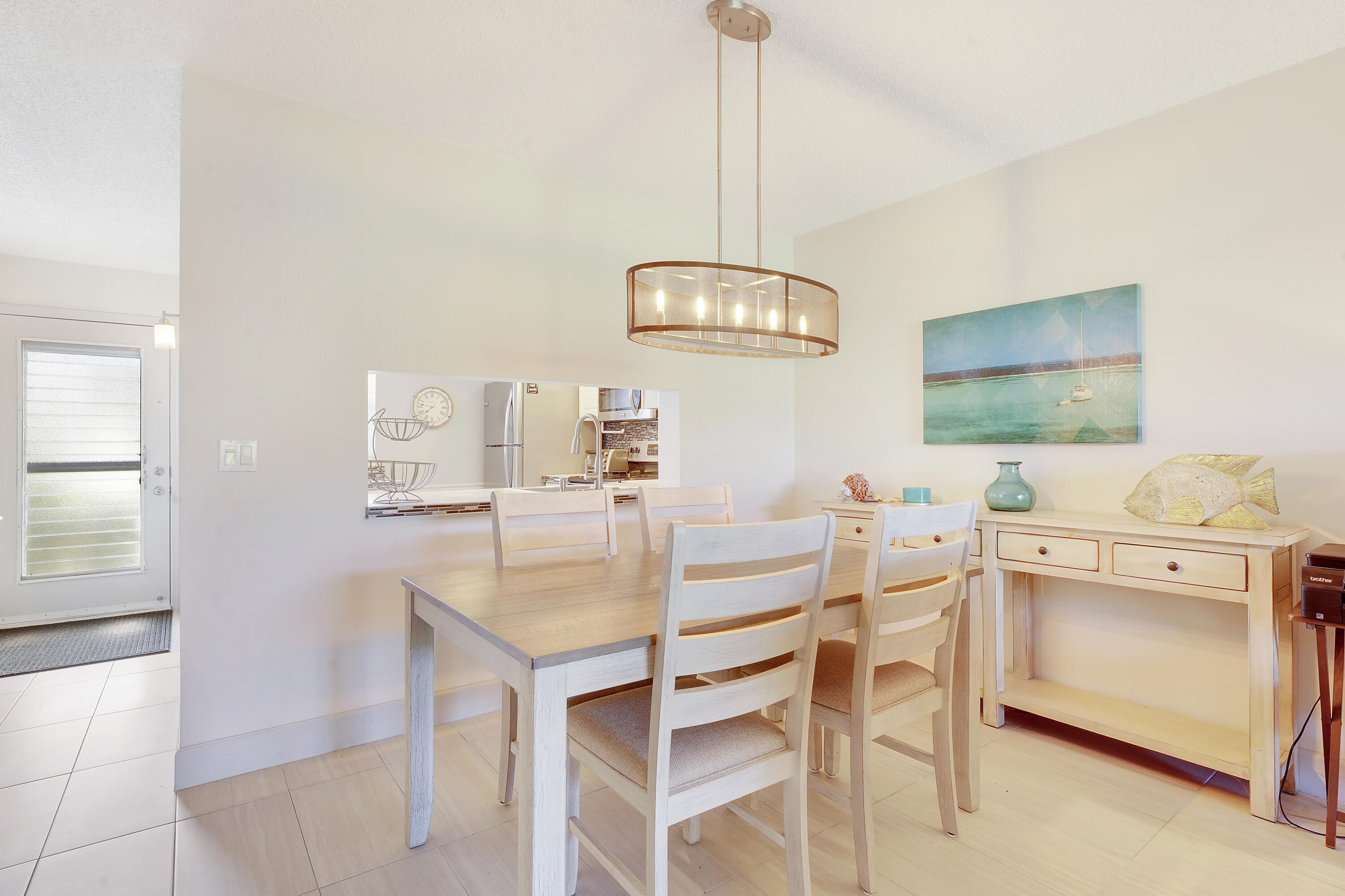 2400 Northeast 1st Lane, Unit 1020 Boynton Beach, FL 33435 - Photo 8 of 34 a view of a kitchen with a dining table chairs and white cabinets