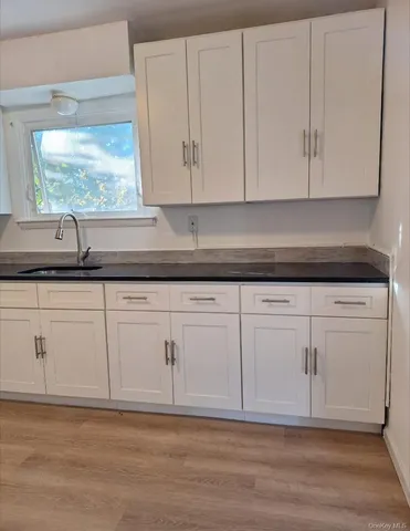 a kitchen with granite countertop white cabinets and a sink