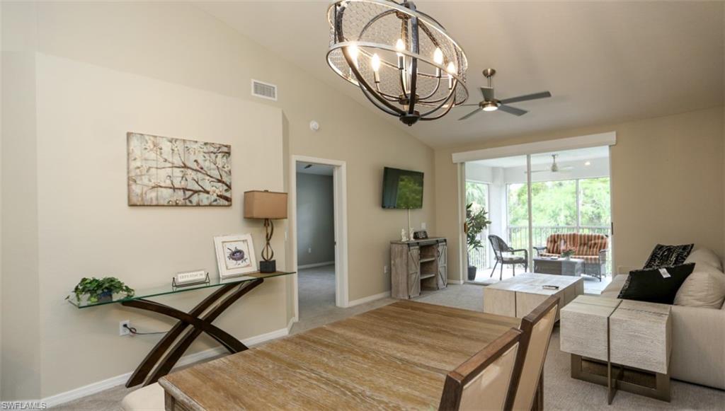 6645 Huntington Lakes Circle, Unit 201 Naples, FL 34119 - Photo 15 of 48 Dining area with light carpet, ceiling fan with notable chandelier, and lofted ceiling