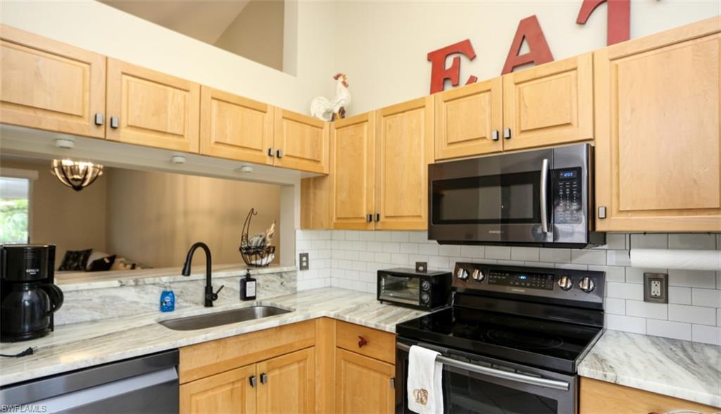 6645 Huntington Lakes Circle, Unit 201 Naples, FL 34119 - Photo 6 of 48 Kitchen featuring sink, light brown cabinets, backsplash, a chandelier, and appliances with stainless steel finishes