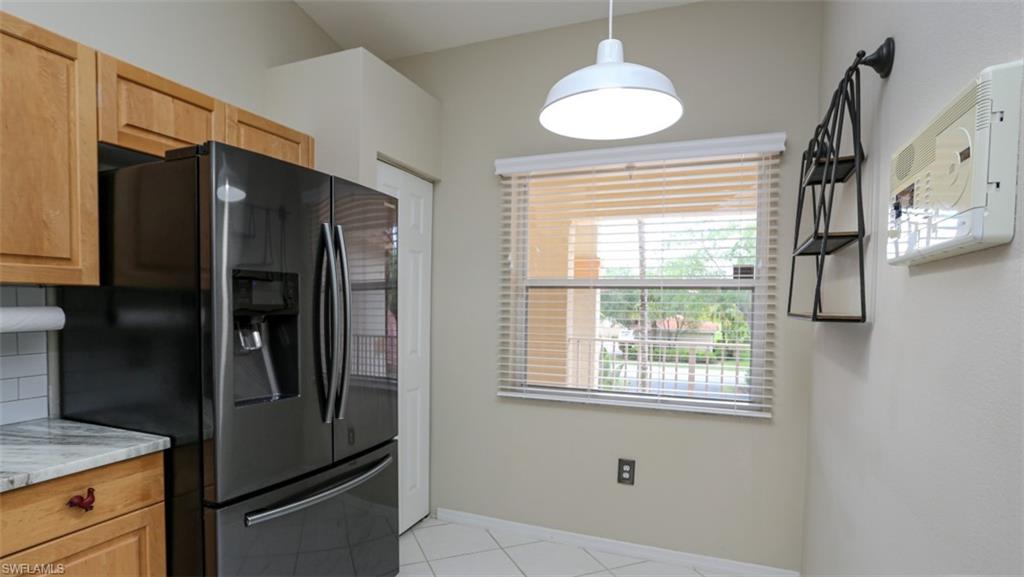 6645 Huntington Lakes Circle, Unit 201 Naples, FL 34119 - Photo 8 of 48 Kitchen with light stone counters, light tile patterned floors, decorative light fixtures, and stainless steel refrigerator with ice dispenser