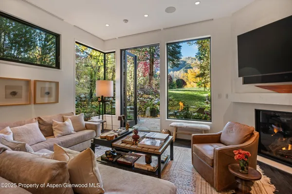 a living room with furniture a flat screen tv and a floor to ceiling window