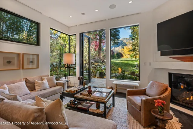 a living room with furniture a flat screen tv and a floor to ceiling window