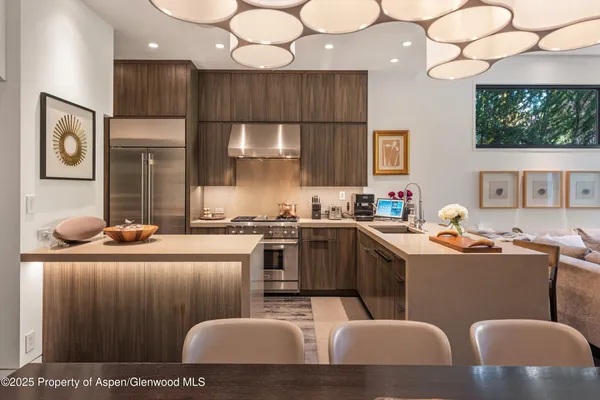 a kitchen with stainless steel appliances kitchen island granite countertop a stove a sink a refrigerator and white cabinets