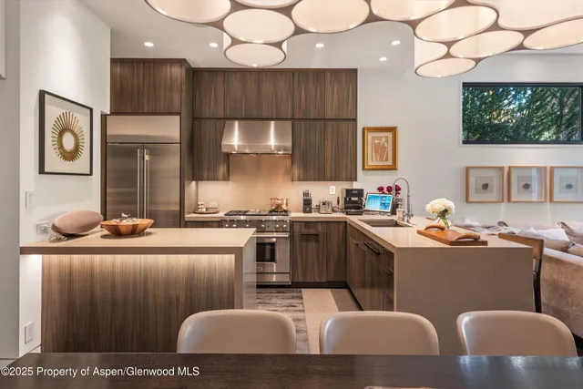 a kitchen with stainless steel appliances kitchen island granite countertop a stove a sink a refrigerator and white cabinets