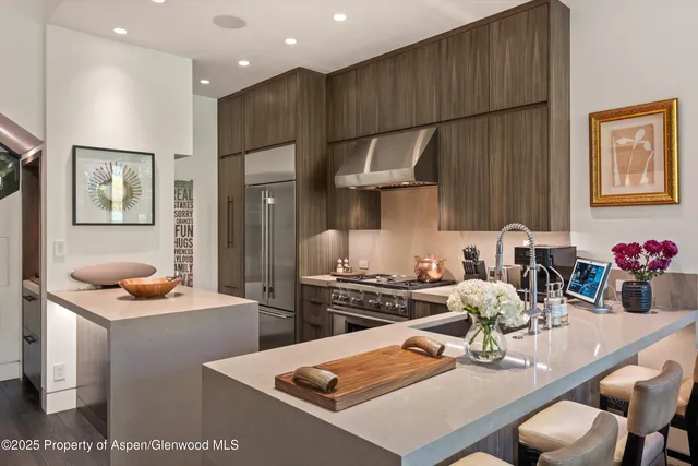 a kitchen with stainless steel appliances kitchen island granite countertop a stove a sink a refrigerator and white cabinets