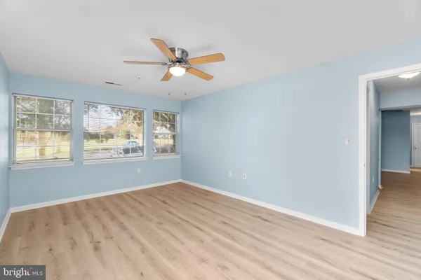 an empty room with wooden floor fan and windows