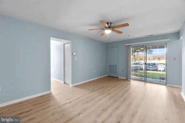 a view of an empty room with a window and wooden floor
