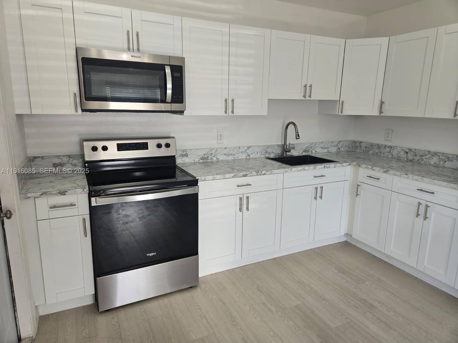 637 West 31st Street Hialeah, FL 33012 - Photo 2 of 20 a kitchen with granite countertop white cabinets and stainless steel appliances