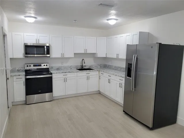 a kitchen with stainless steel appliances white cabinets and a refrigerator