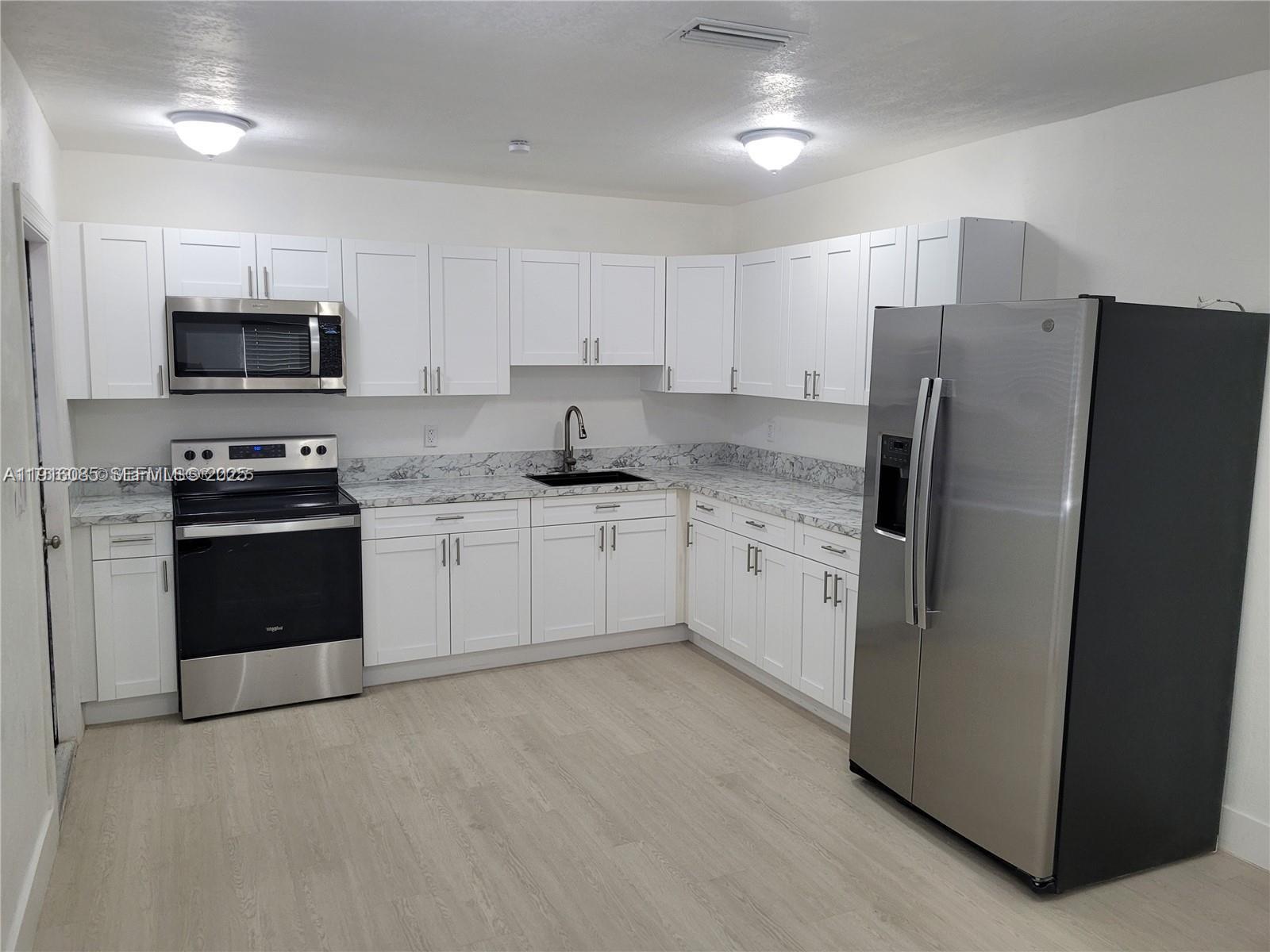 637 West 31st Street Hialeah, FL 33012 - Photo 3 of 20 a kitchen with stainless steel appliances white cabinets and a refrigerator