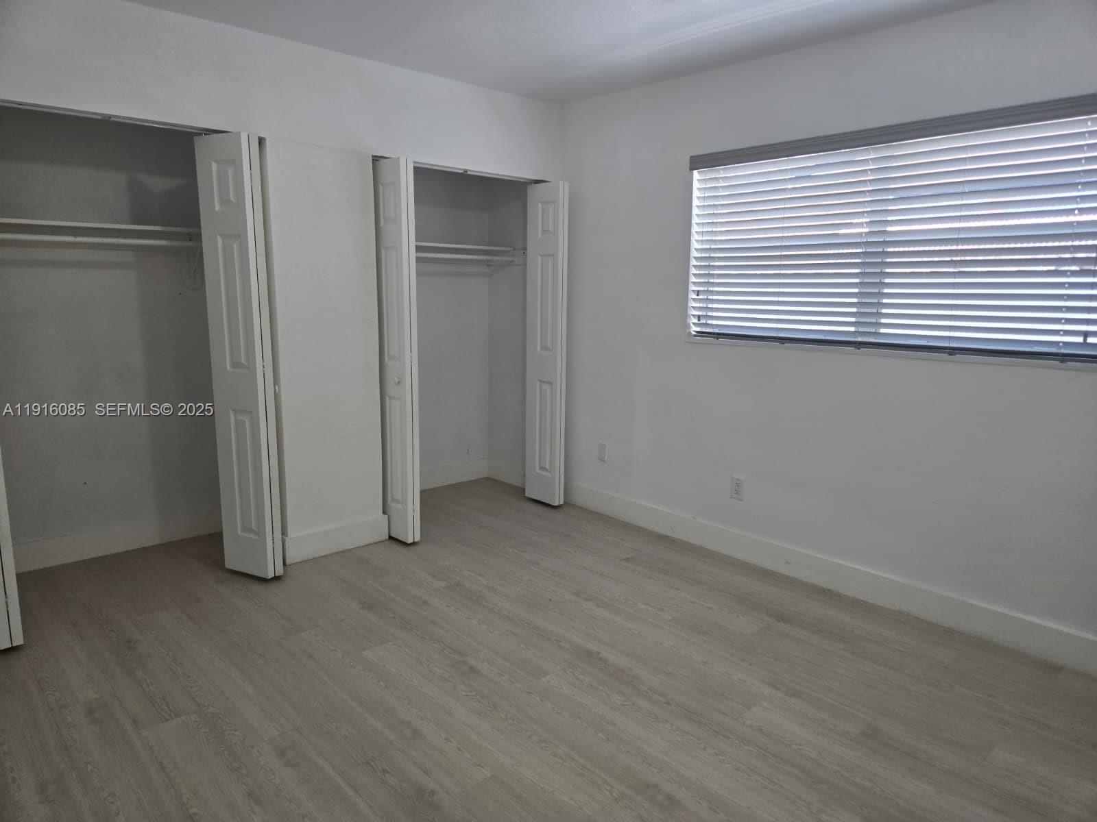 637 West 31st Street Hialeah, FL 33012 - Photo 10 of 20 an empty room with wooden floor and windows