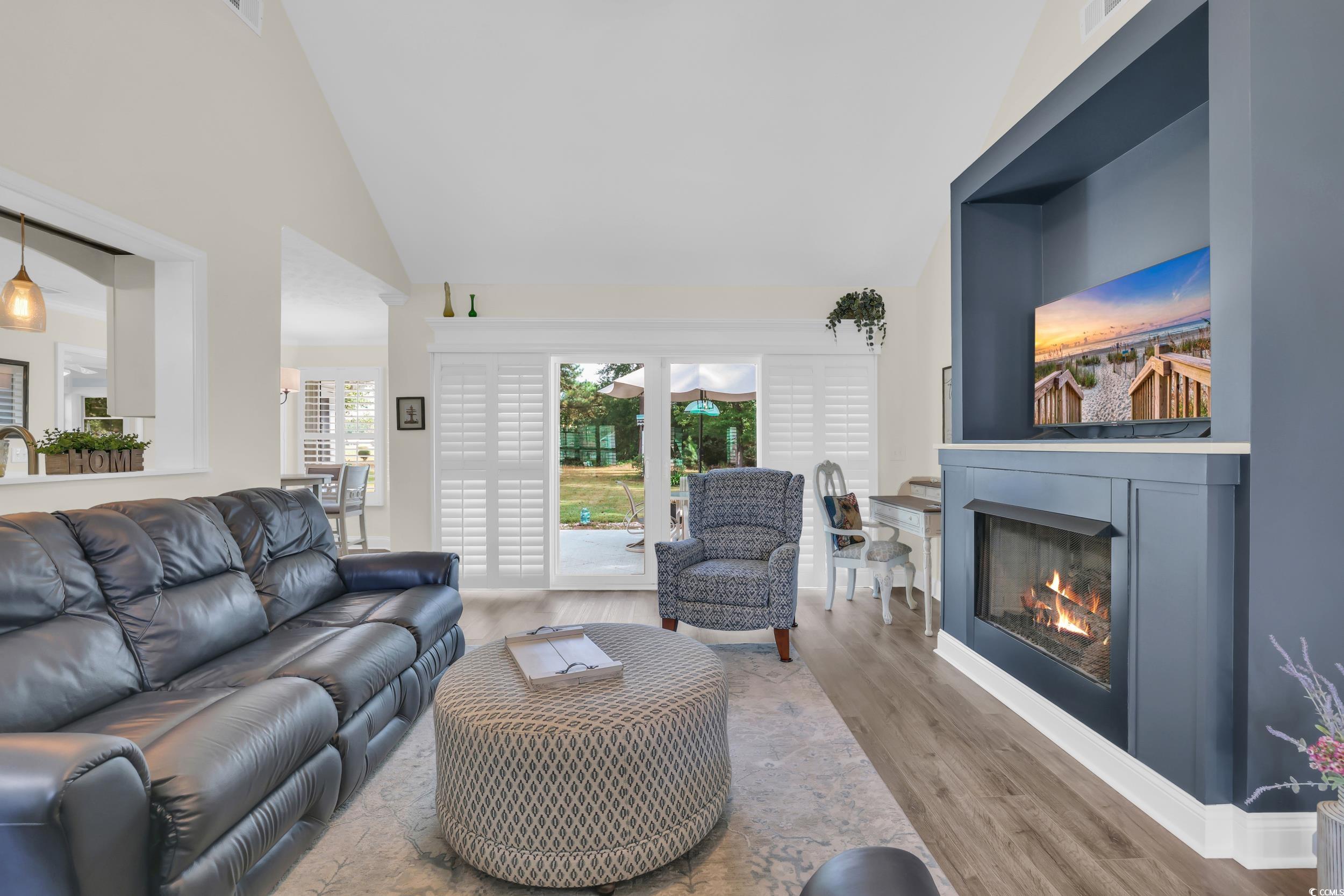 442 Deer Watch Circle Longs, SC 29568 - Photo 11 of 40 Living area featuring wood finished floors, high vaulted ceiling, and a glass covered fireplace