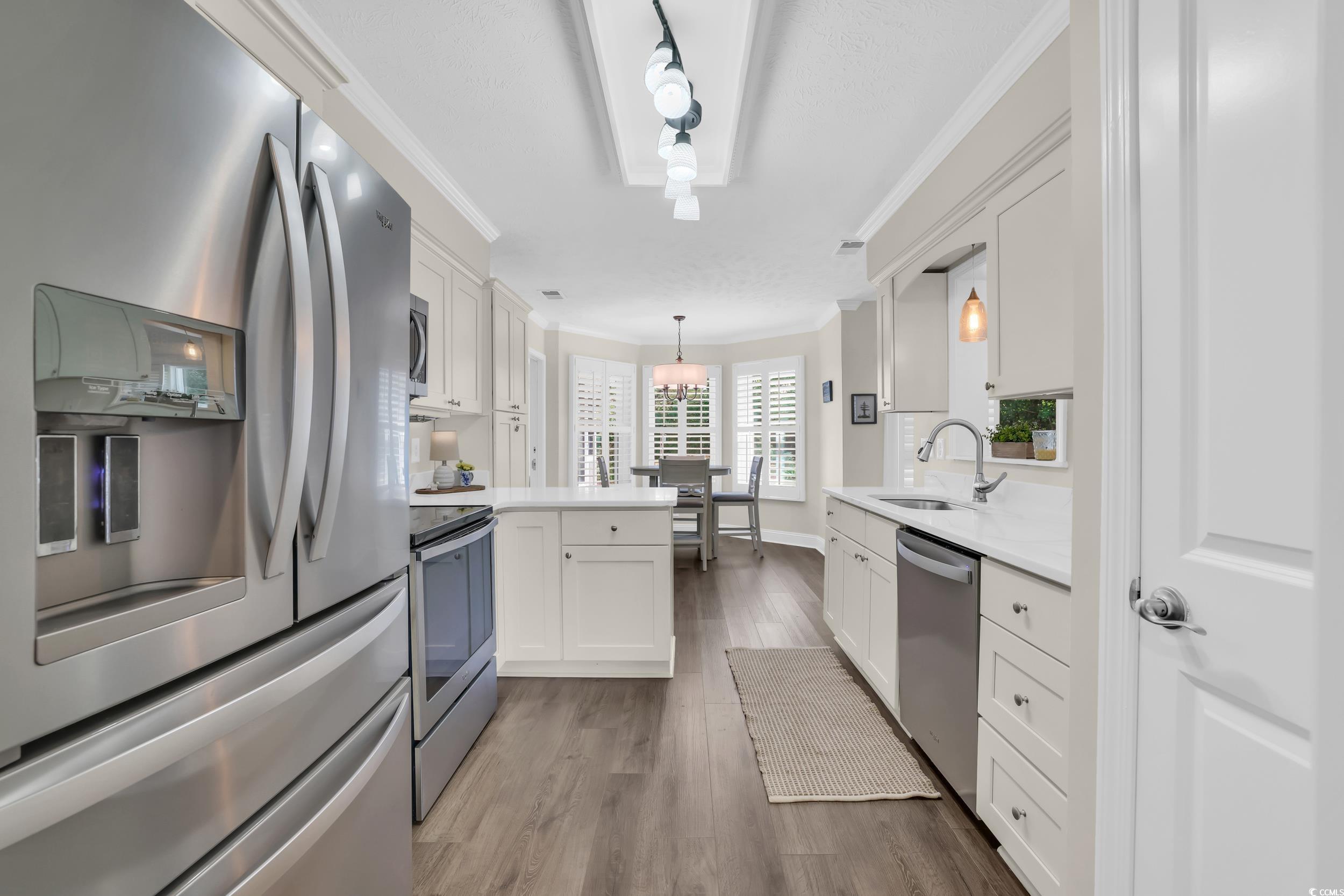 442 Deer Watch Circle Longs, SC 29568 - Photo 12 of 40 Kitchen with stainless steel appliances, a peninsula, white cabinets, dark wood-type flooring, and ornamental molding
