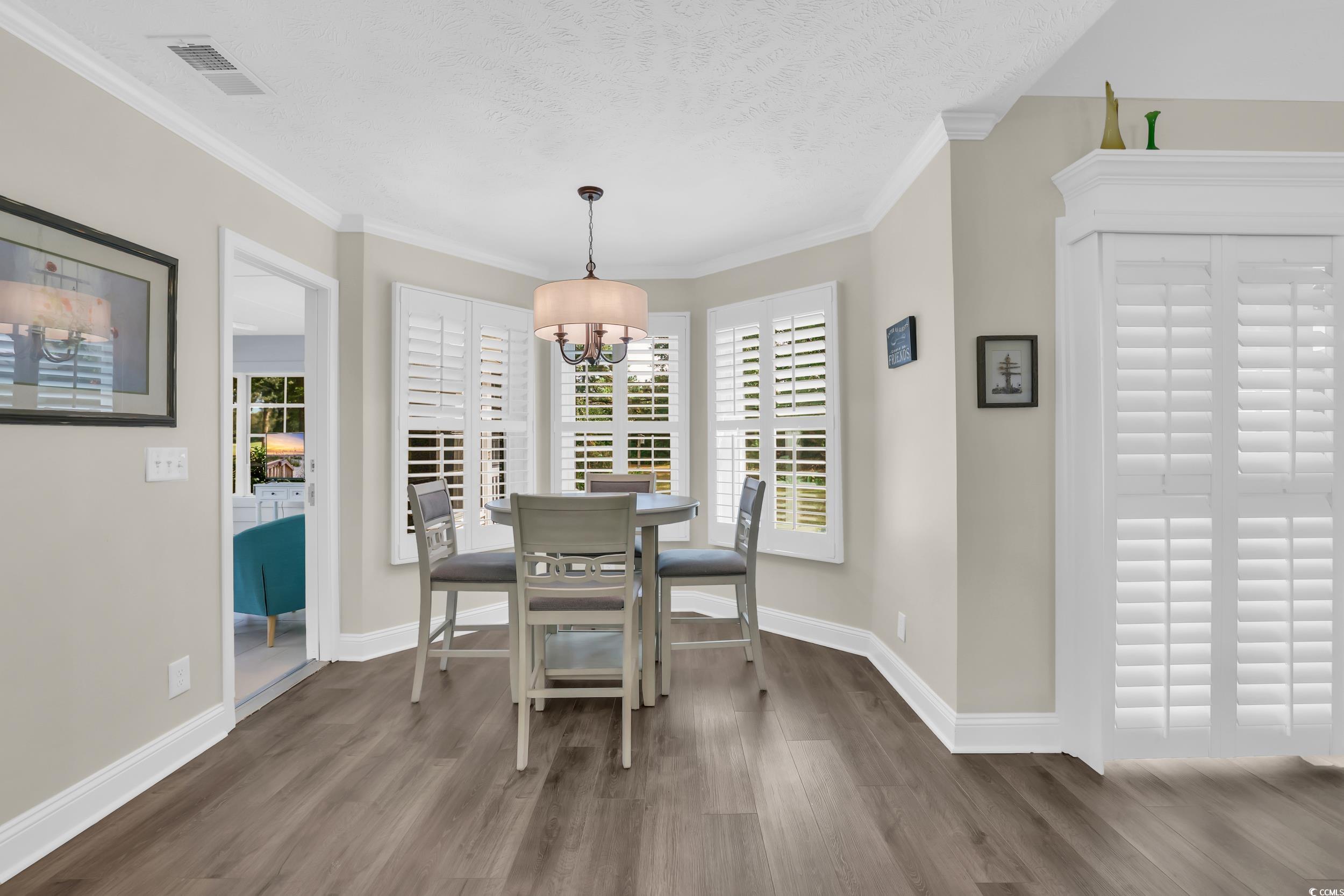 442 Deer Watch Circle Longs, SC 29568 - Photo 14 of 40 Dining area featuring healthy amount of natural light, wood finished floors, ornamental molding, a textured ceiling, and a chandelier