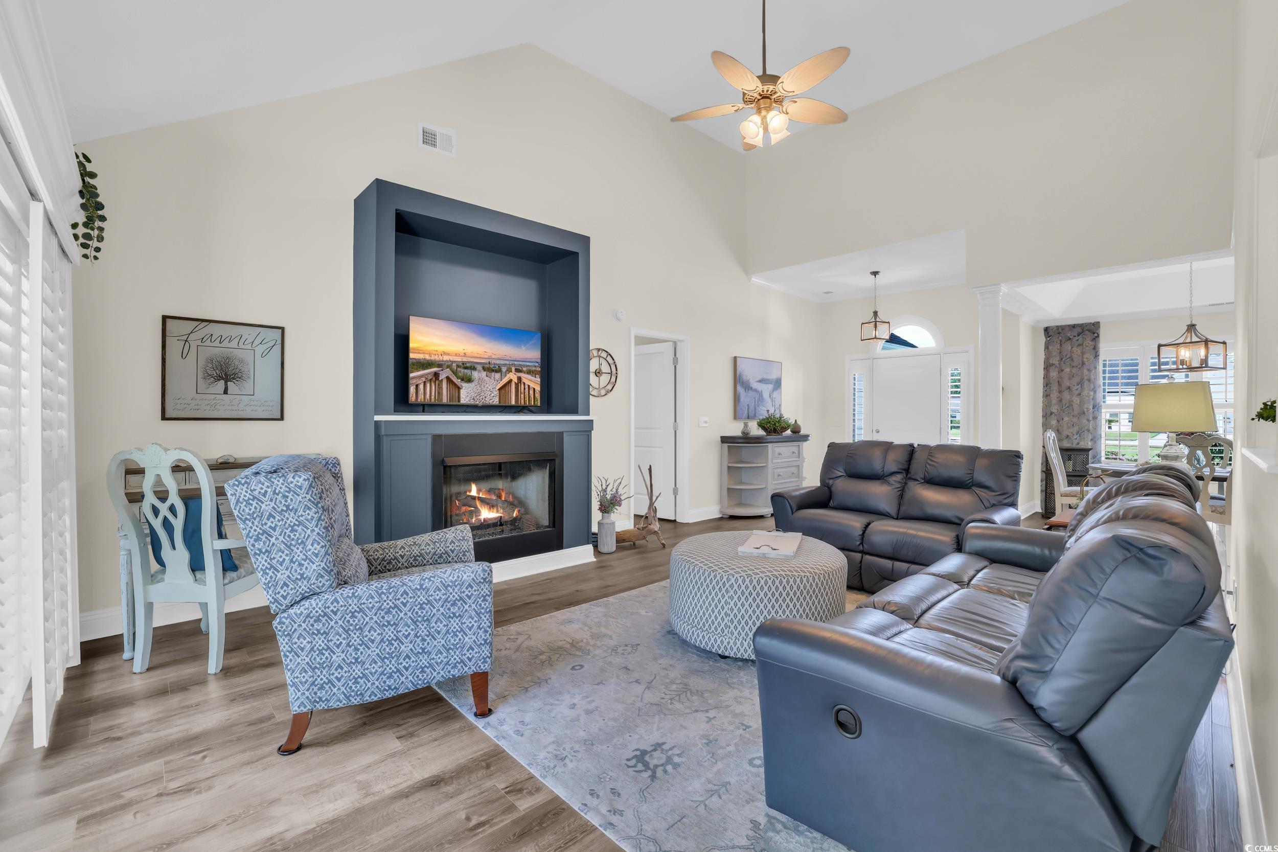 442 Deer Watch Circle Longs, SC 29568 - Photo 2 of 40 Living area featuring wood finished floors, a glass covered fireplace, ceiling fan, high vaulted ceiling, and ornate columns