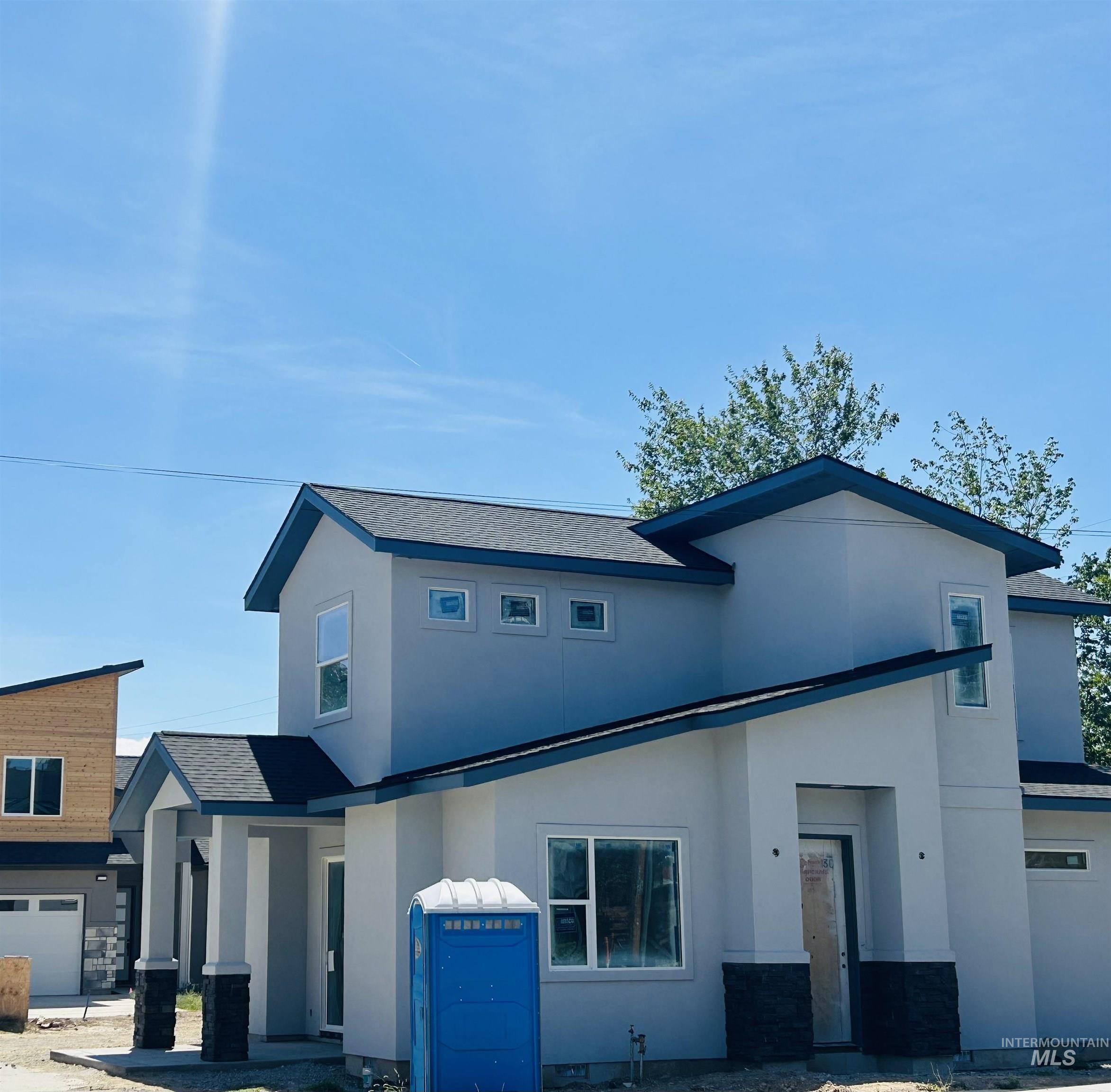 View of front of home with stucco siding and a shingled roof