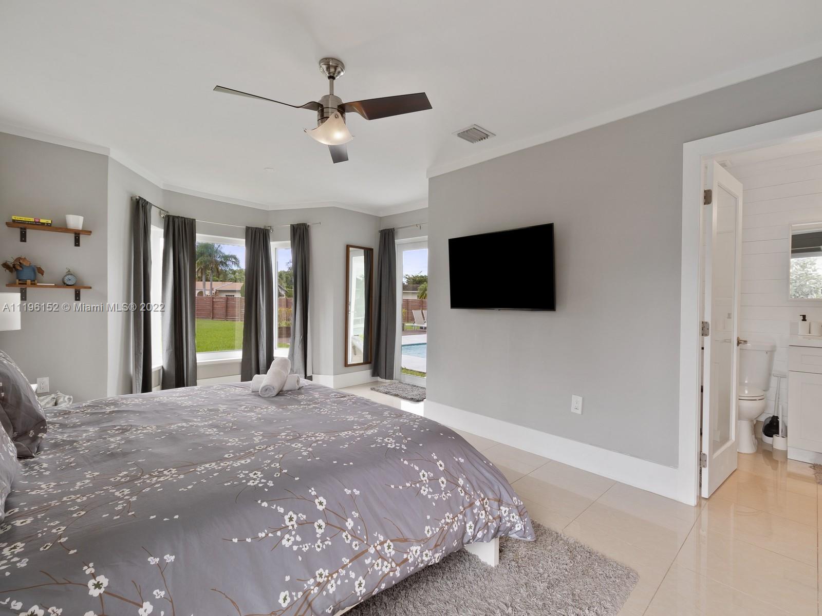 14250 Southwest 97th Avenue Miami, FL 33176 - Photo 29 of 38 a bedroom with a bed a flat screen tv and a chandelier