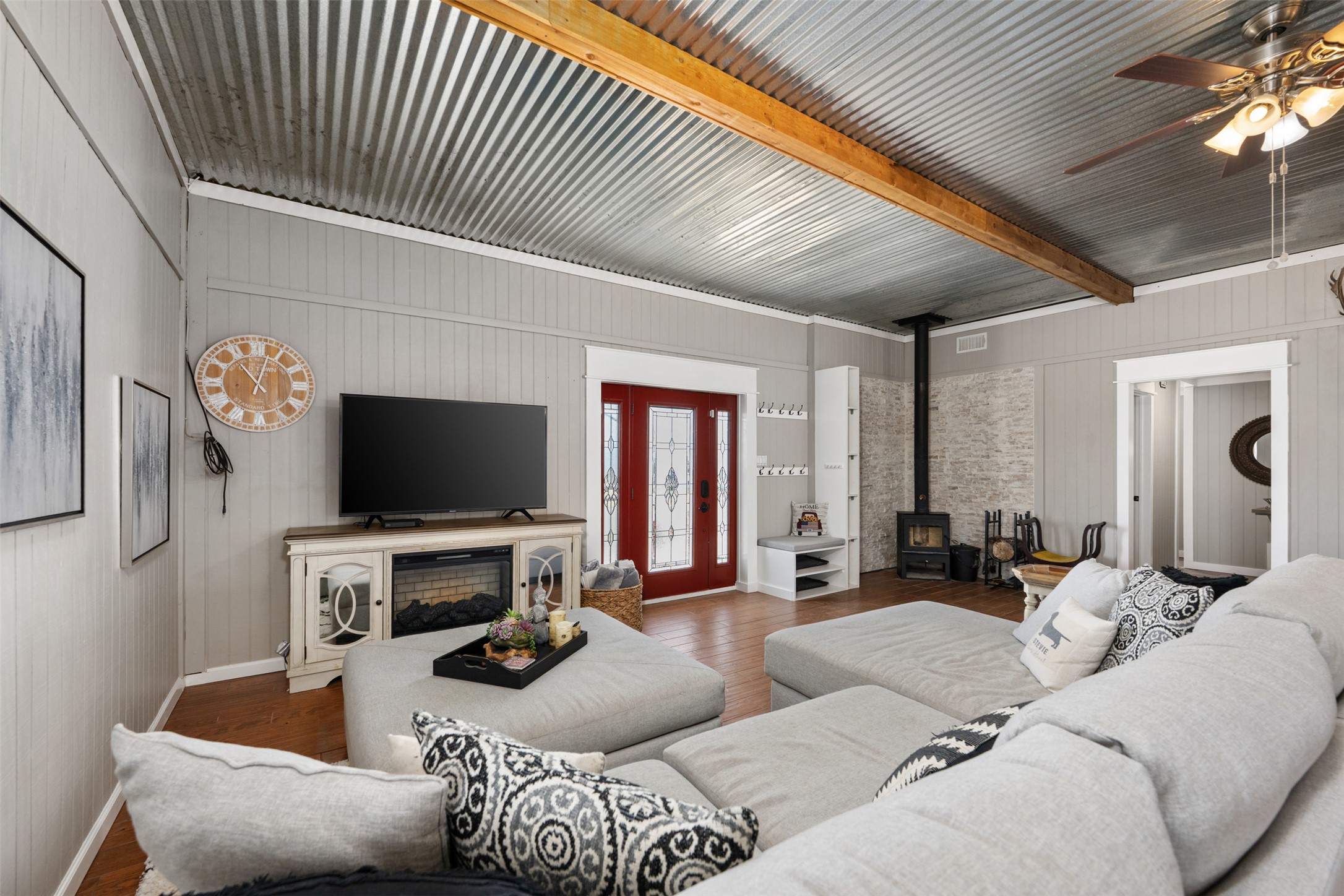 6501 County Road 239 Jarrell, TX 76537 - Photo 3 of 40 Living room featuring a ceiling fan, a wood stove, wood finished floors, and wooden walls
