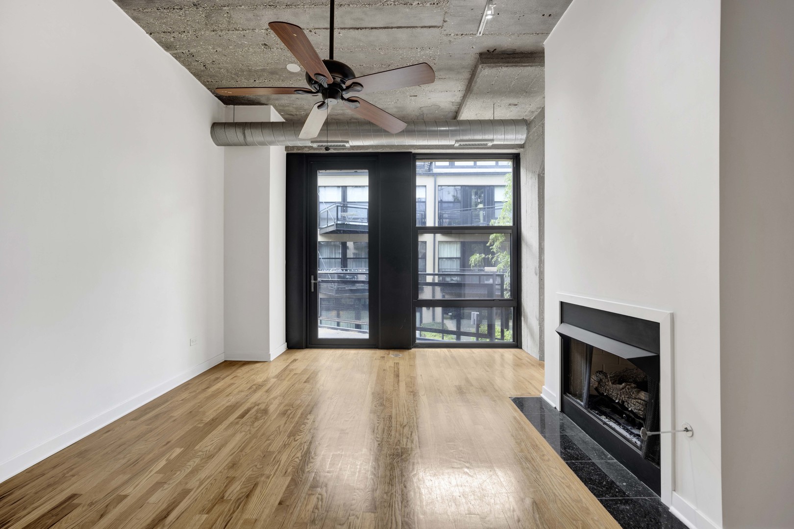 1151 West 14th Place, Unit 209 Chicago, IL 60608 - Photo 7 of 17 a view of an empty room with wooden floor fireplace and a window
