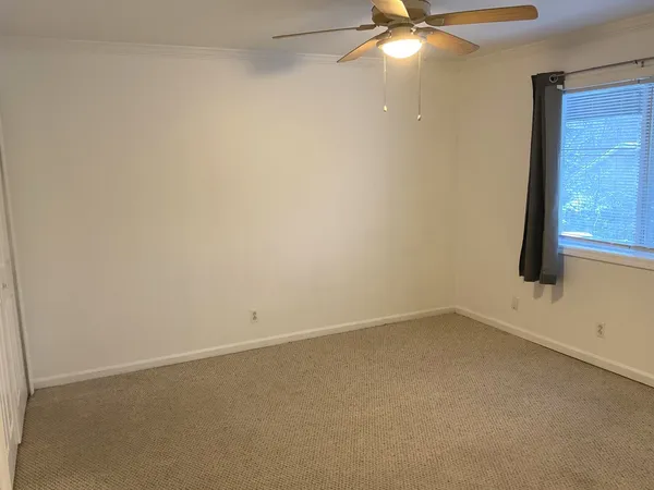 an empty room with a window and a fan