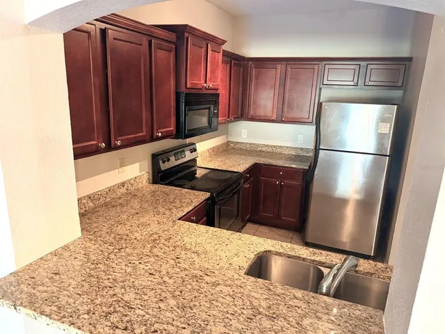 a kitchen with granite countertop a refrigerator stove and microwave