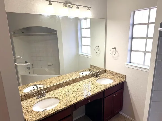 an empty room with wooden floor chandelier fan and windows