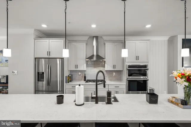 a kitchen with stainless steel appliances kitchen island granite countertop a refrigerator a stove a sink and a dining table with wooden floor