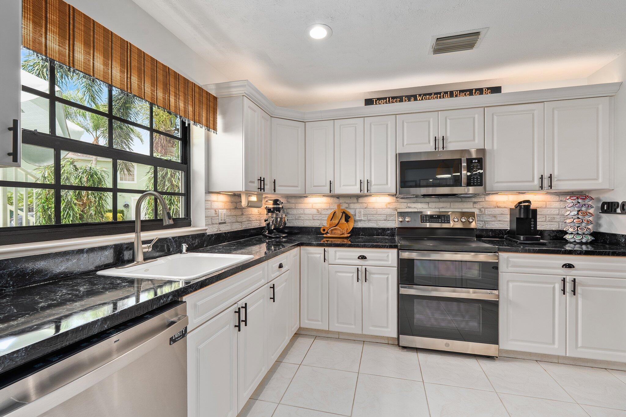 2186 Southeast Wild Meadow Circle Port St. Lucie, FL 34952 - Photo 12 of 57 a kitchen with granite countertop a sink stainless steel appliances and cabinets