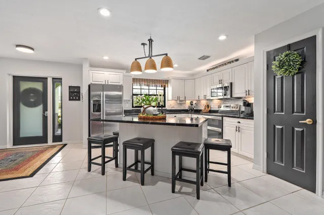 a kitchen with stainless steel appliances a dining table chairs refrigerator and sink
