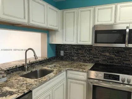 a kitchen with granite countertop a sink a stove and cabinets