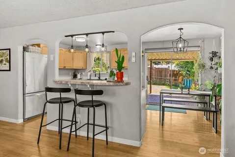 a kitchen with stainless steel appliances granite countertop a stove a refrigerator a oven with white cabinets and wooden floor