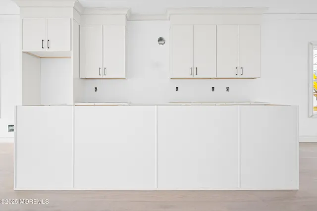 a kitchen with white cabinets and window