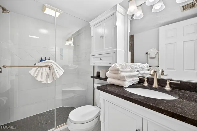 a bathroom with a granite countertop sink a toilet and a mirror