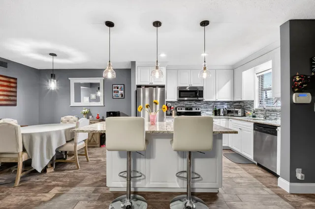 a kitchen with stainless steel appliances granite countertop a table chairs refrigerator and microwave