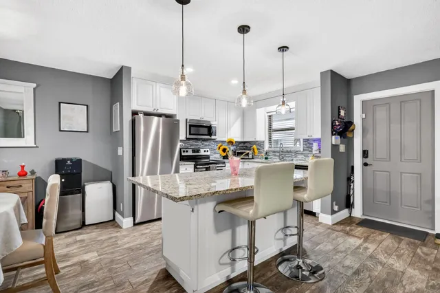 a kitchen with stainless steel appliances a refrigerator a stove a sink dishwasher and a dining table with wooden floor