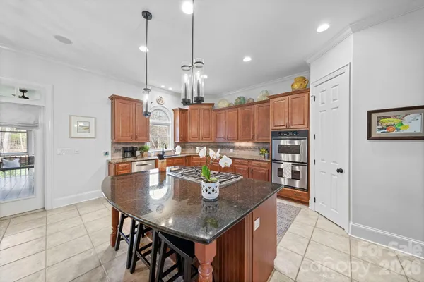 a kitchen with granite countertop a stove a sink a dining table and chairs