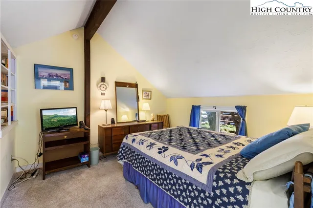 a bedroom with a bed and a flat tv screen on dresser