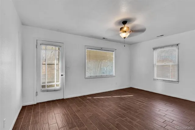 a view of an empty room with wooden floor and a window